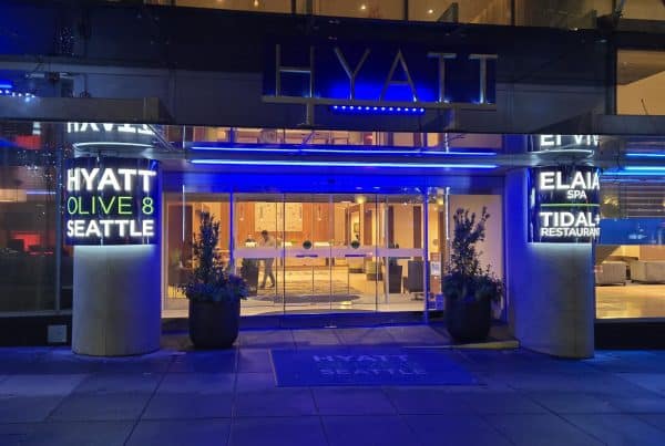 Entrance of a Hyatt hotel at night with illuminated signs for "Hyatt Olive 8 Seattle," "Elaia Spa," and "Tidal+ Restaurant.